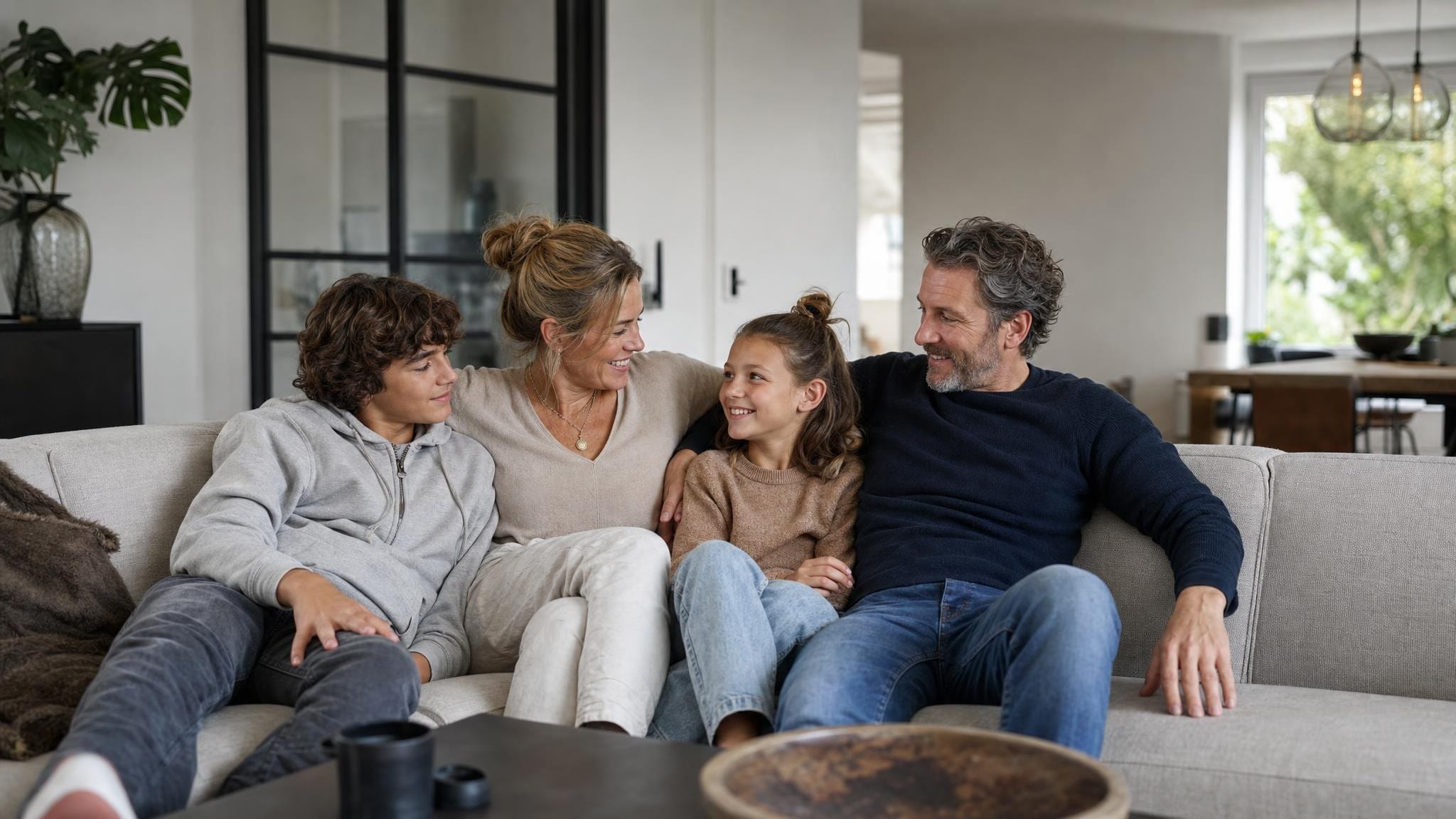 Samengesteld gezin met kinderen van verschillende leeftijden zit samen op de bank in een lichte, moderne woonkamer